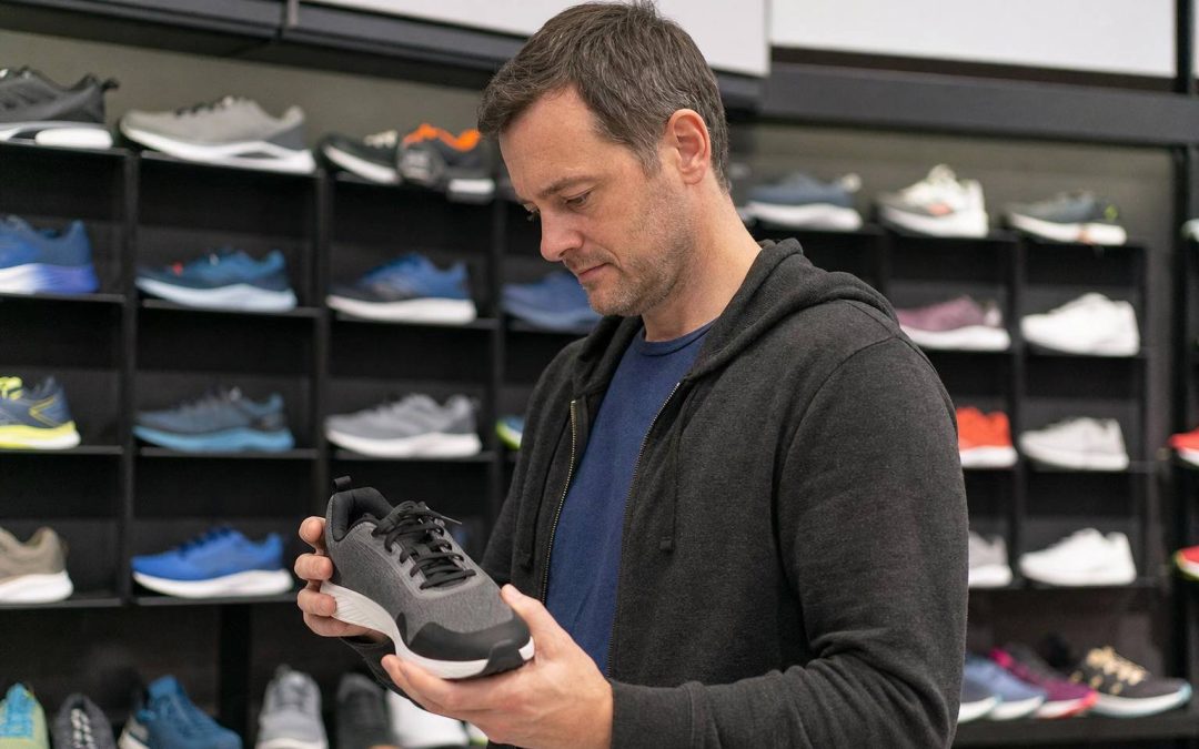 A runner examining a running shoe while choosing a pair in a shop